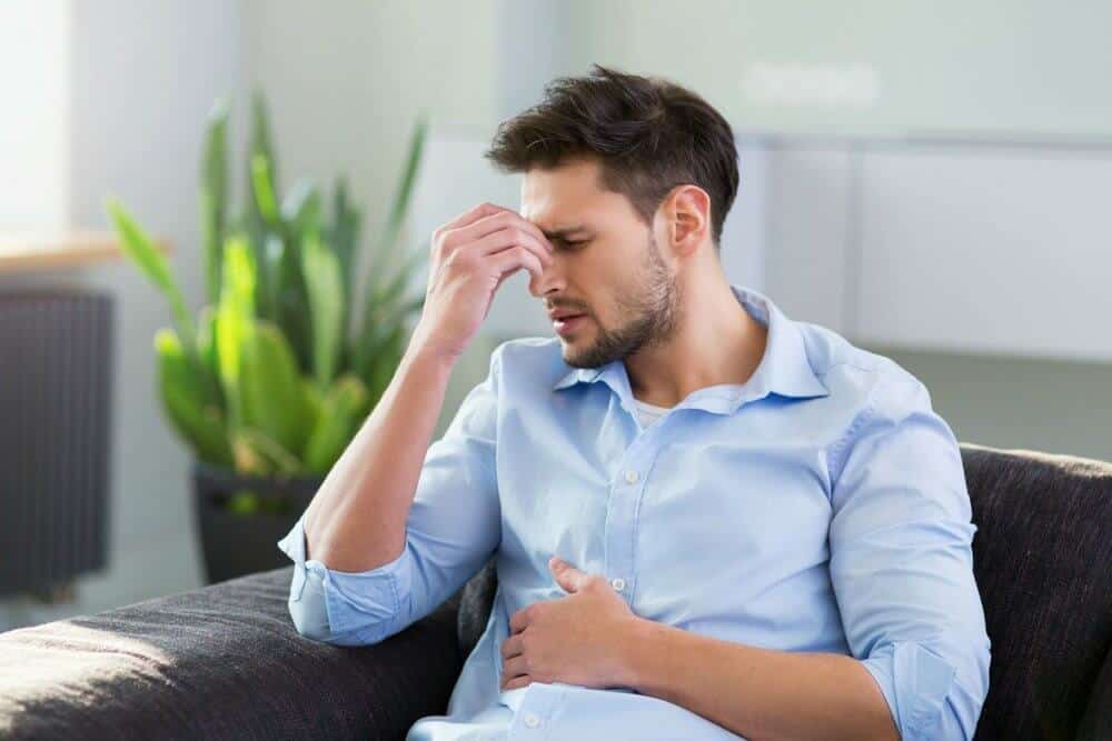 lighthousetreatment-percocet-withdrawal-and-detox-article-photo-of-man-on-sofa-having-headache-406432471