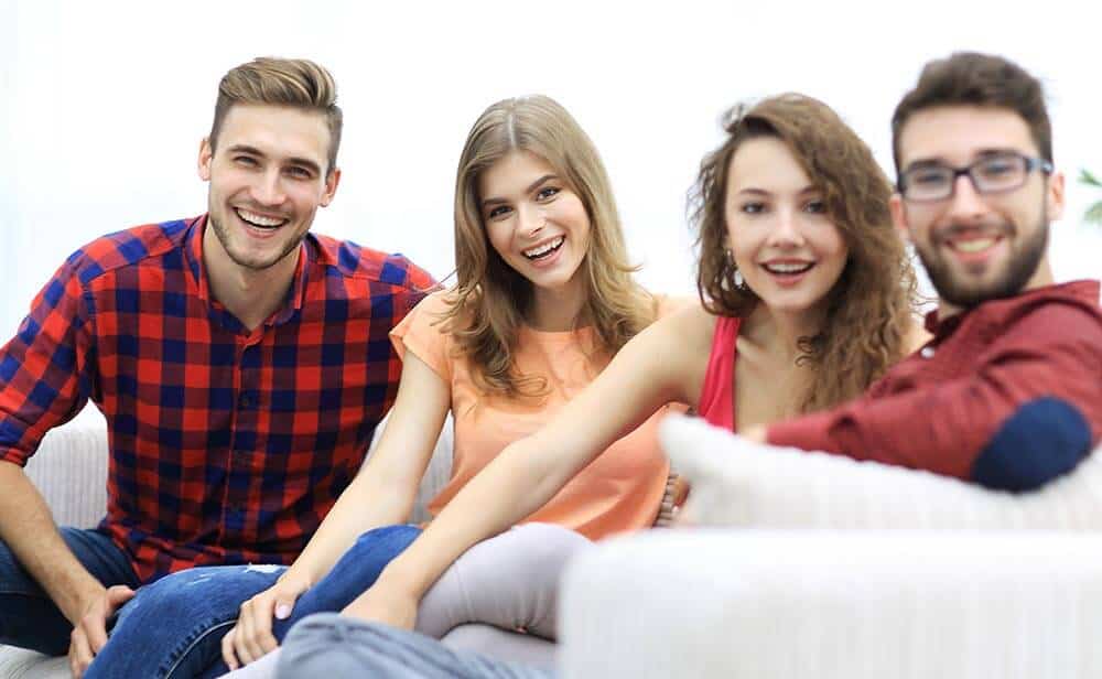 lighthousetreatment-who-really-needs-rehab-what-are-some-alternatives-photo-group-of-cheerful-friends-sitting-on-sofa-717129448