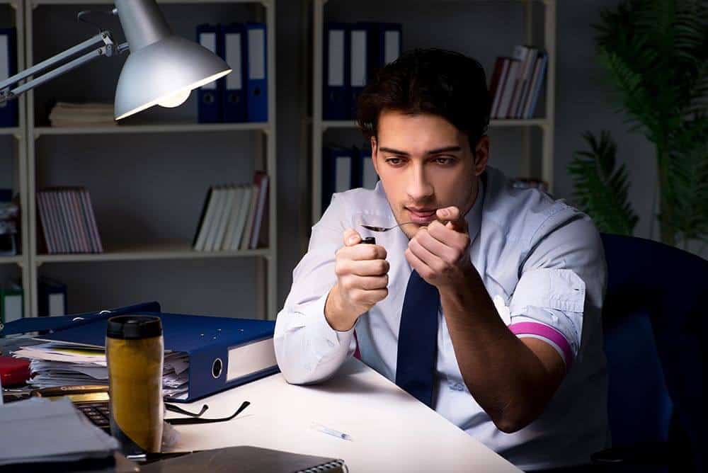 lighthousetreatment-the-relation-between-iq-and-drug-addiction-article-photo-employee-relieving-stress-from-overtime-with-drugs-narcotics-1064371199