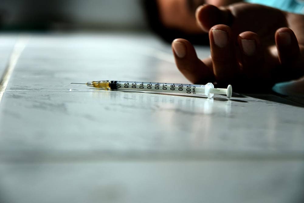 lighthousetreatment-what-is-heroin-cut-with-article-photo-syringe-with-heroin-in-front-of-drug-addict-male-648581200