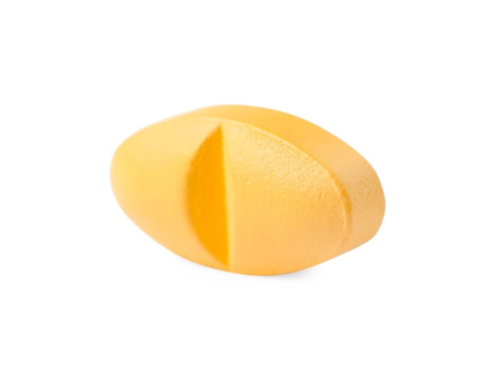 A single orange Xanax alprazolam pill on a white surface 
