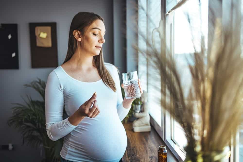 A pregnant woman taking trazodone pills and glass of water