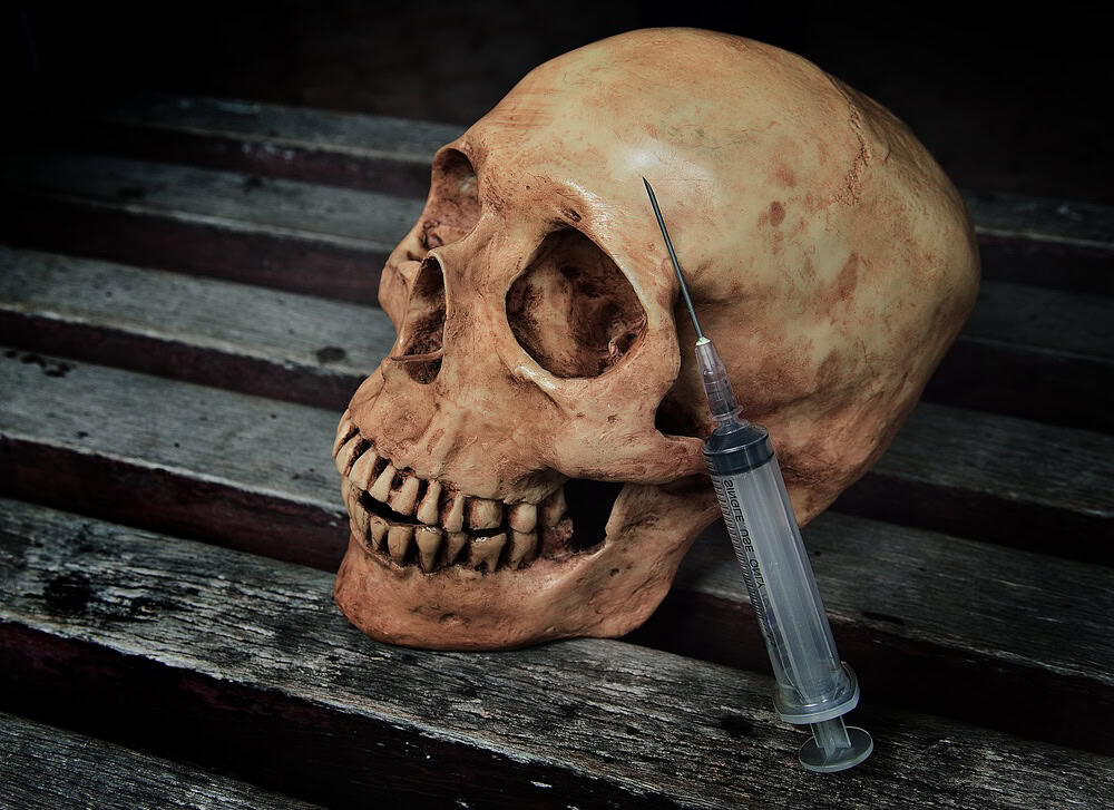 A skull and a syringe on a block surface