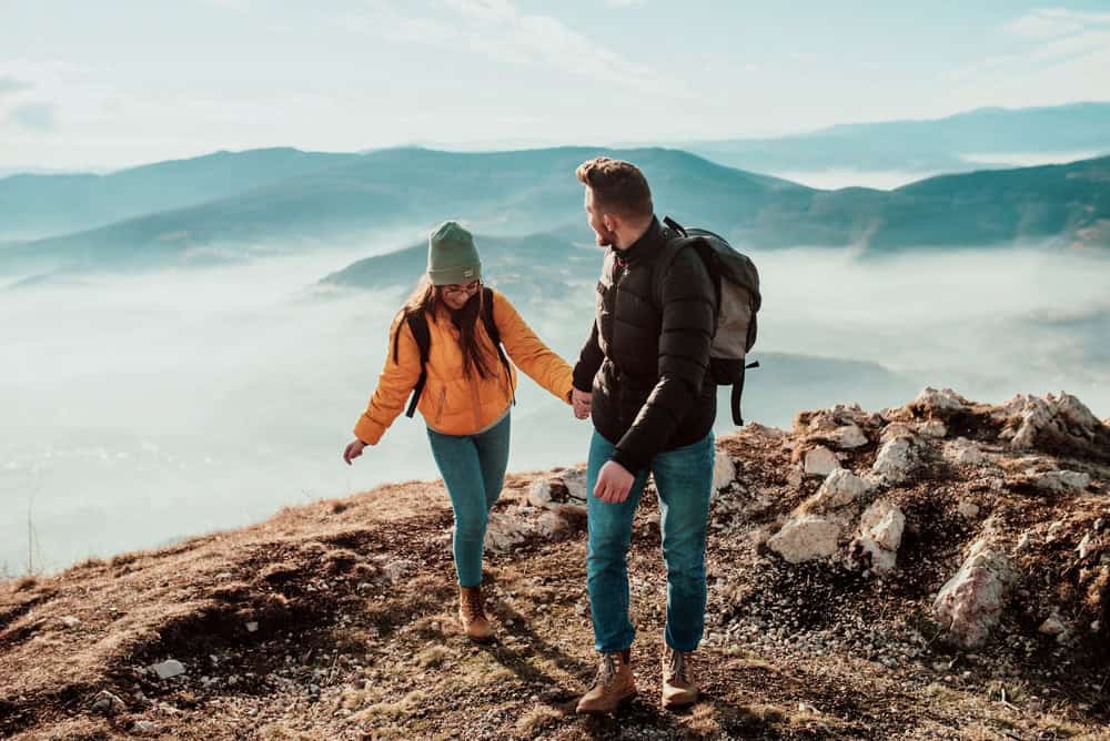 Couple hiking on top of a mountain with fog surrounding them