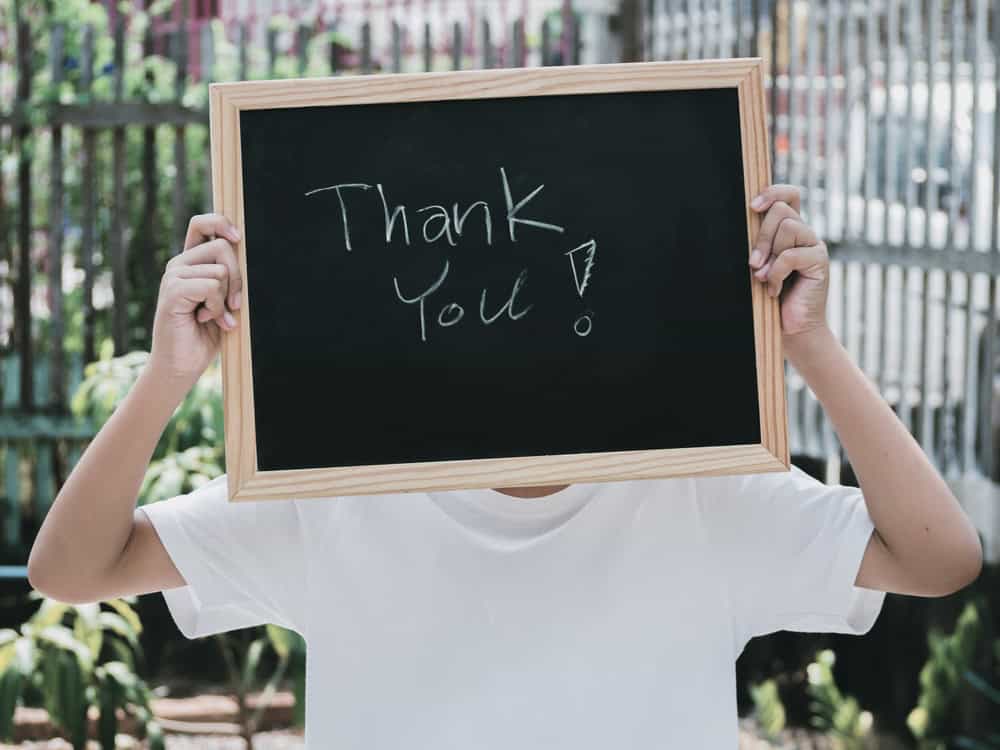 Man holding a small board with Thank You written on it