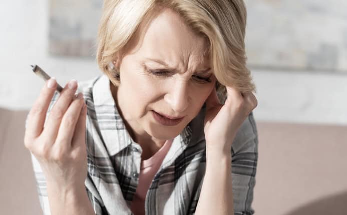 Woman with a hangover holding a weed joint 