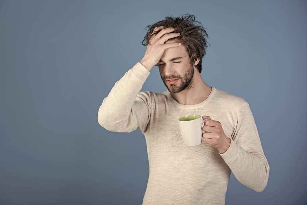 Man with a hangover holding a mug