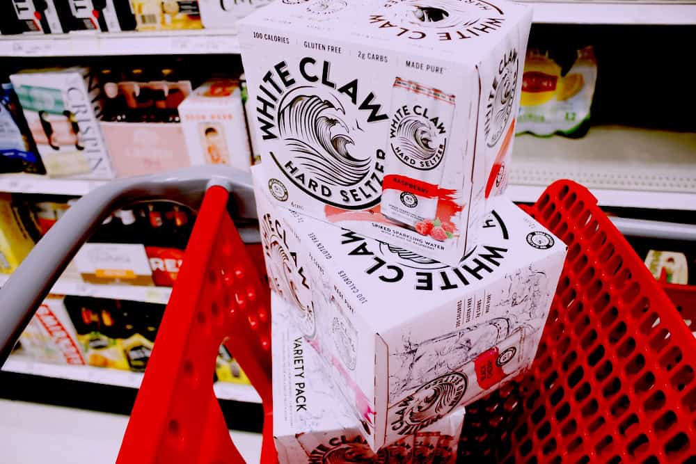 Boxes of White Claw hard seltzer stacked inside a red supermarket trolley
