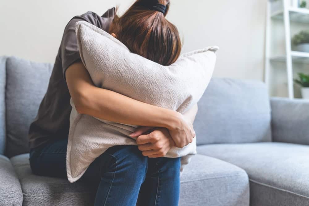 Woman hugging a pillow crying