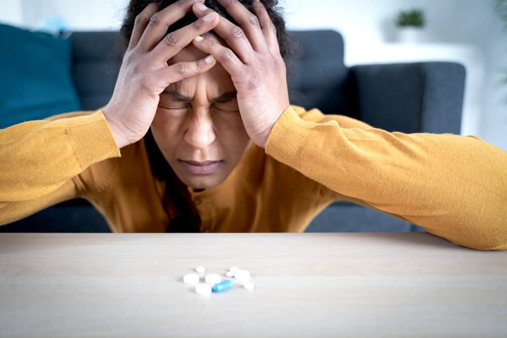 Anxious woman looking at pills on the table