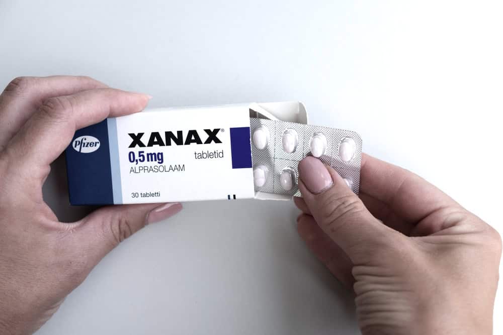 Hand removing pills from a Xanax box