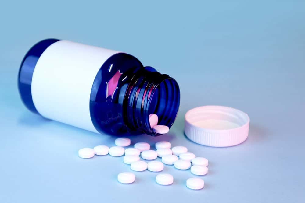 White alprazolam pills from a blue drug bottle