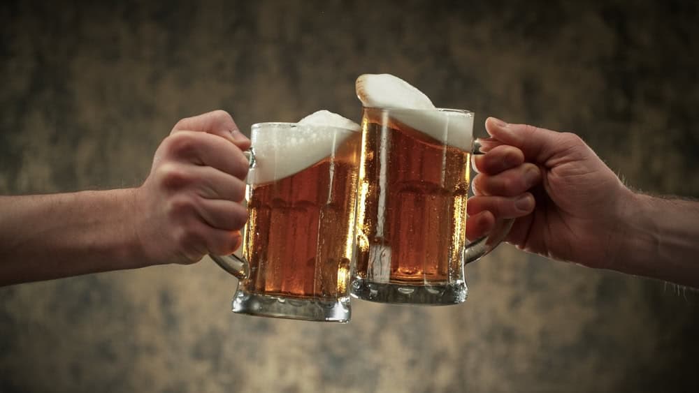 Two pints of beer being clicked together 