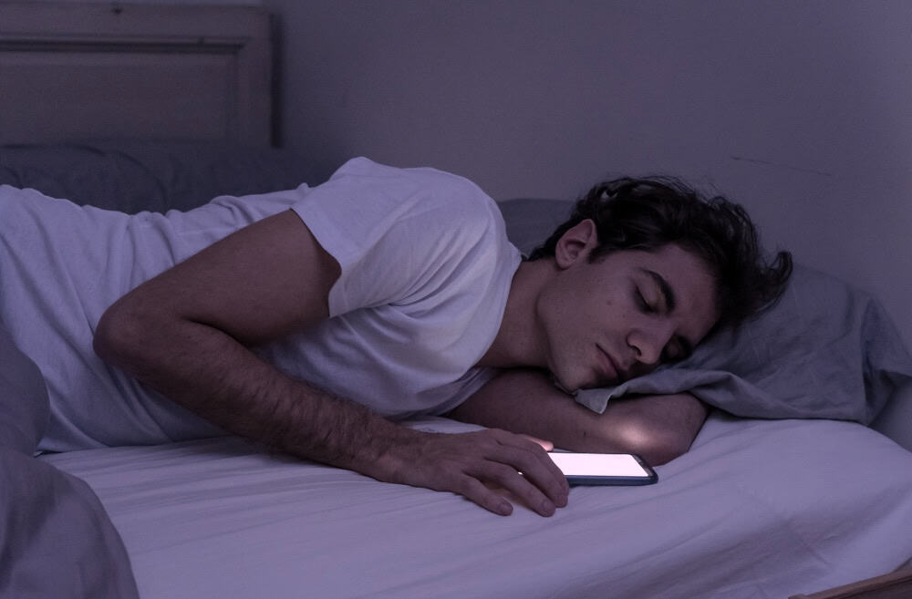 Man who fell asleep on the bed with his phone still on