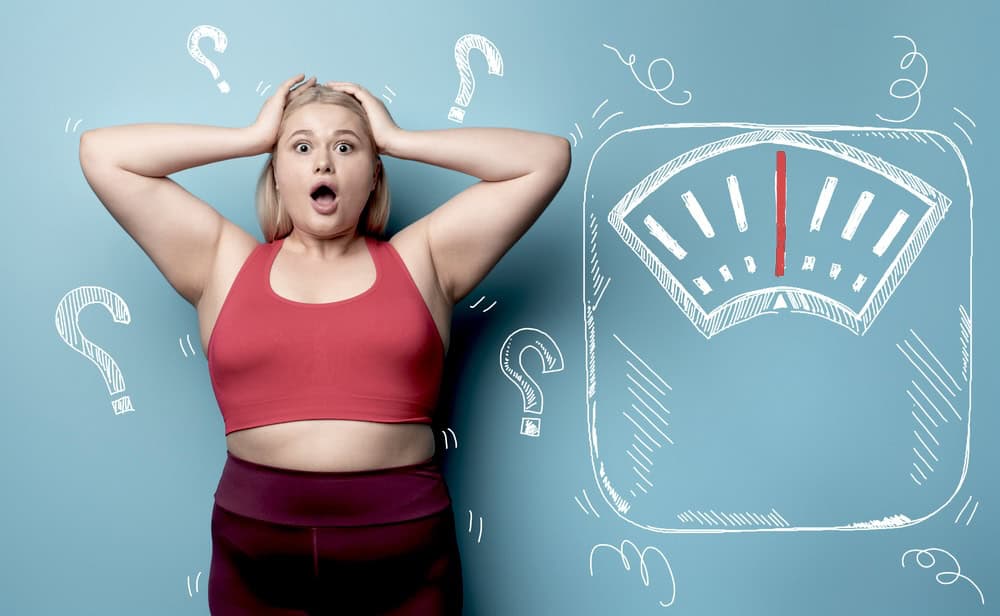 Woman in a red sports bra panicking about her weight, weighing scale illustration in the background