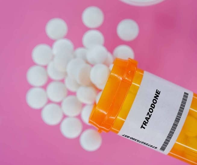 Orange pill bottle with Trazodone bottle, white pills pouring out