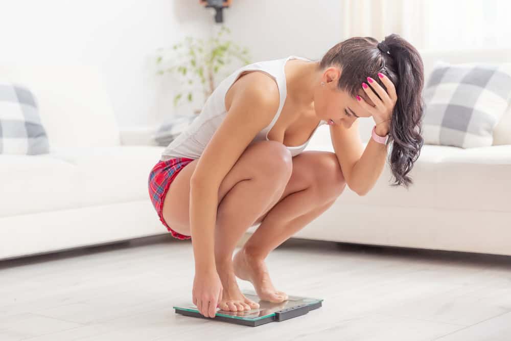 Woman on a weighing scale, on a seated position