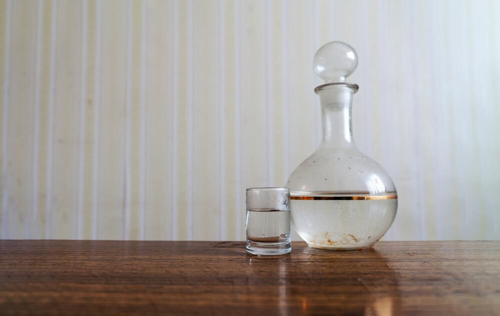 Antique looking decanter of vodka on a wooden table 