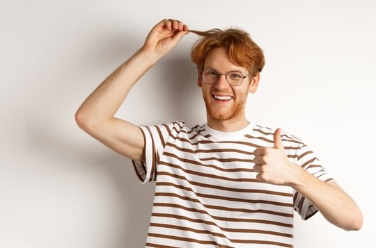 Man holds up his red hair while doing an o a thumbs up sign