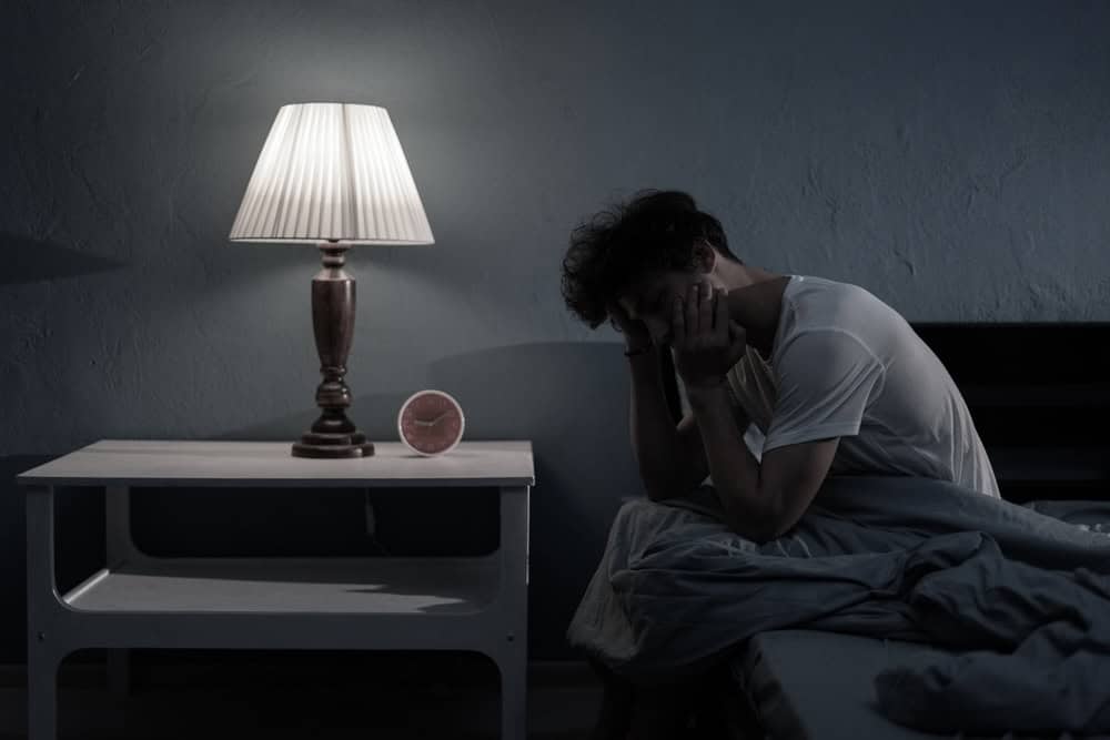 Man sitting on the bed not being able to sleep