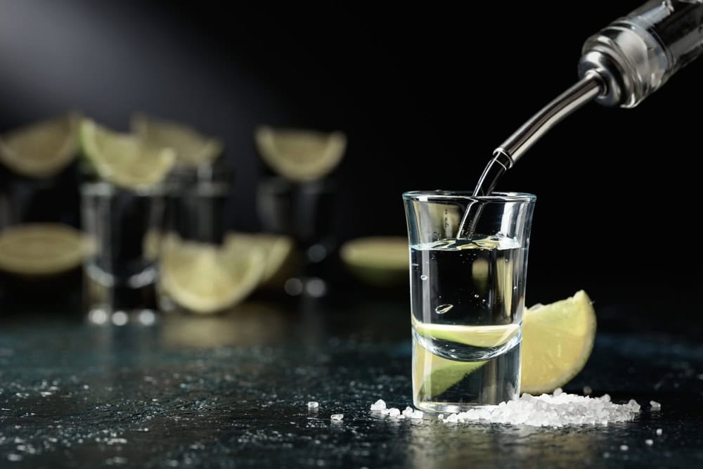Tequila being poured into a shot glass from a tequila that went bad