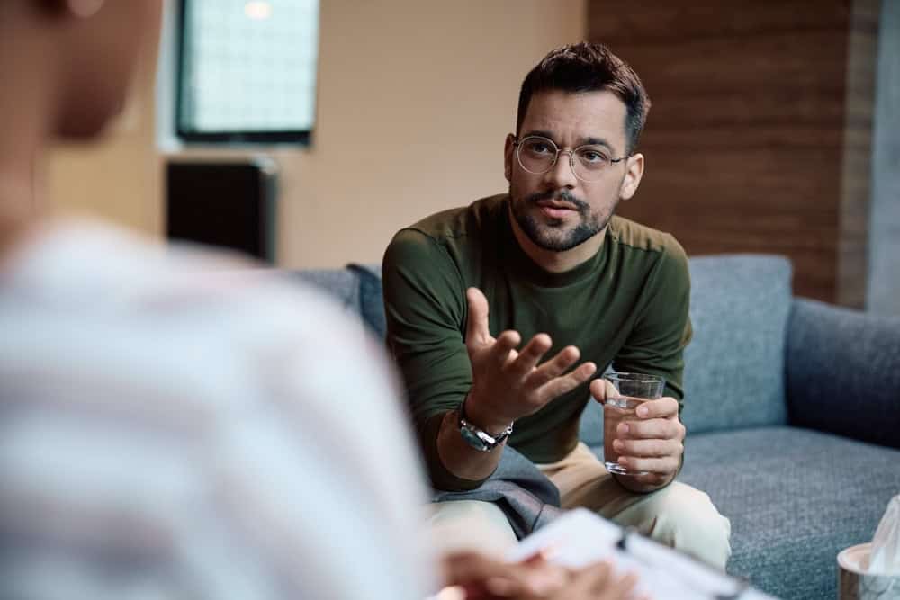 Man wearing green shirt and glasses talking to an addiction specialist about cocaine addiction 