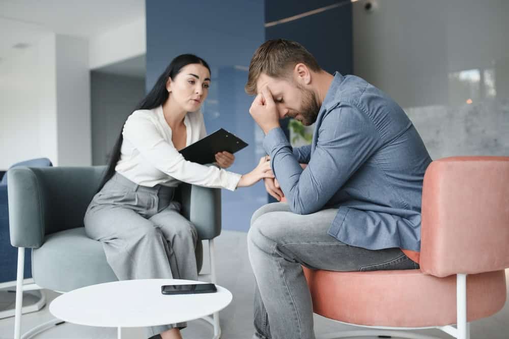 Adult male looks upset with his cocaine addiction while a therapist comforts him