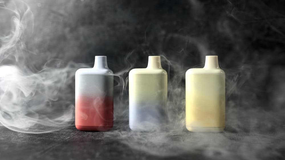 3 vaping device on a table surrounded by smoke