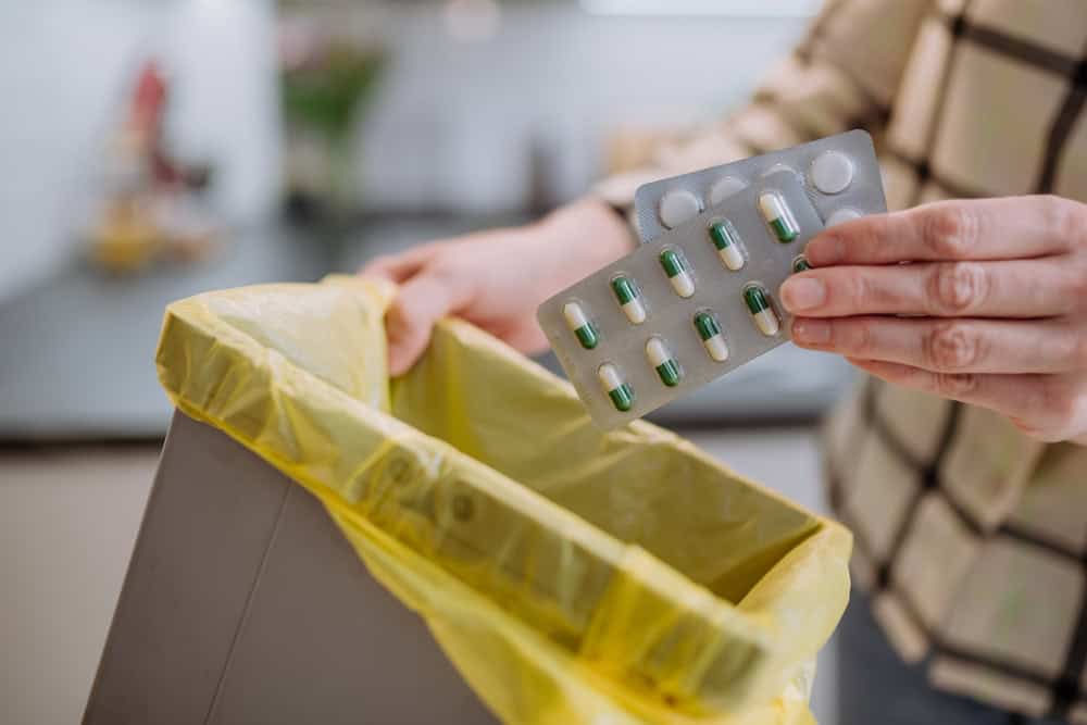 Woman throwing expired Adderall and other drugs in the trash