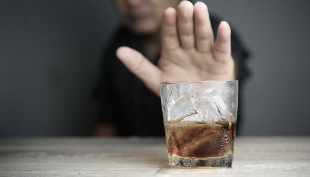 Man refusing an alcoholic drink being offered to him by showing his palm