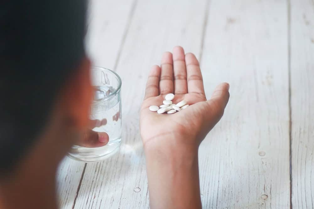 Man holding out his hand with white pills alprazolam 