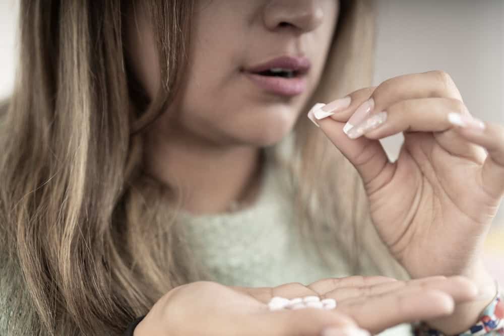 Woman taking an opioid pill wondering if Xanax is an opioid