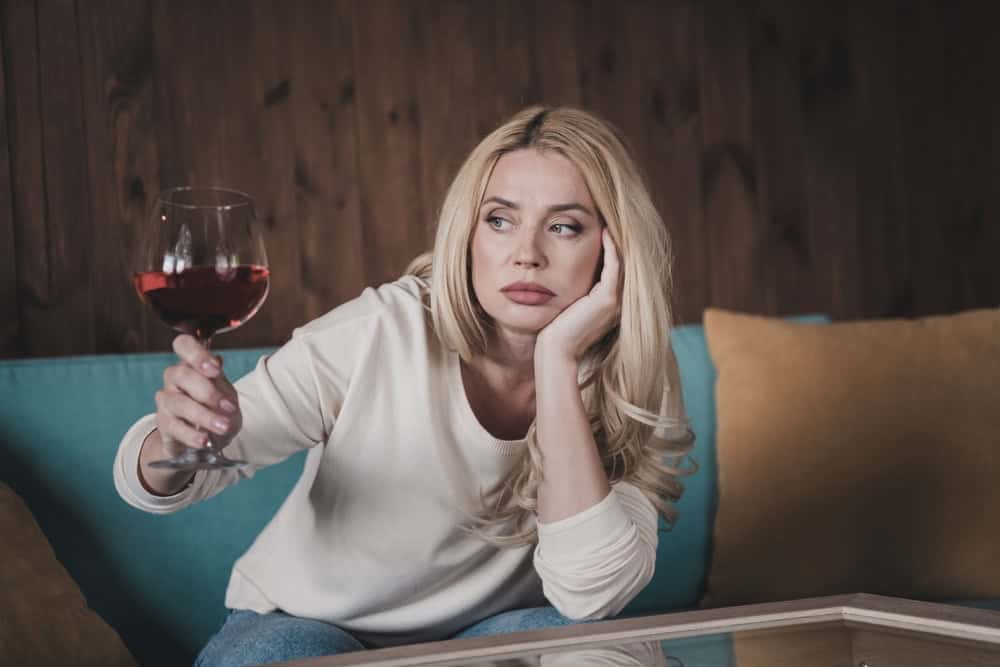 Bored female holding a glass of wine to deal with her emotions