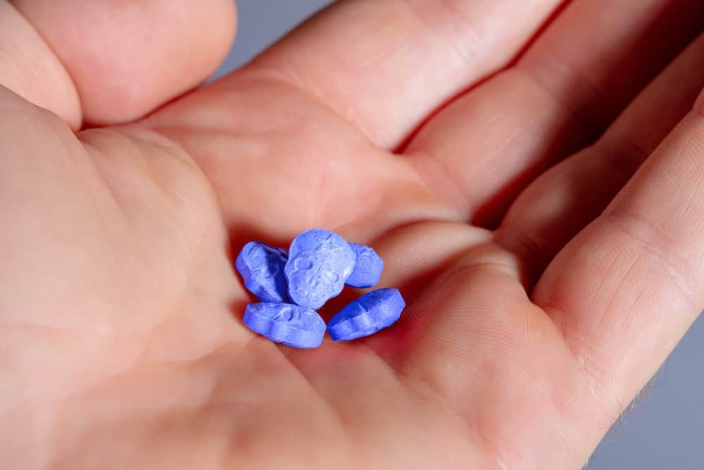 Palm with blue skull-shaped ecstasy MDMA pills