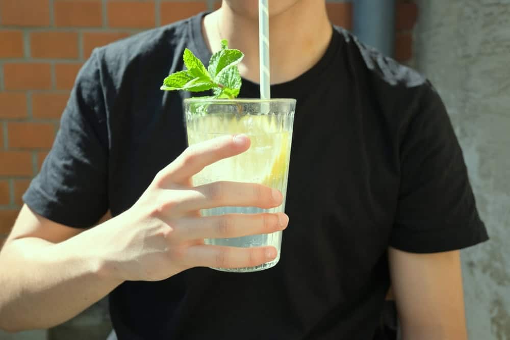 A man in a black shirt holding a non-alcoholic lemonade drink during the summer season