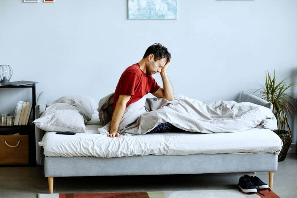 A man with a hangover woke up from sleeping on the couch