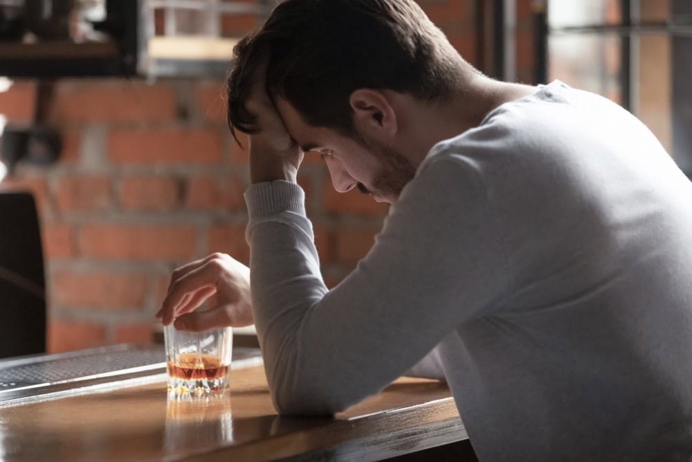 Man looking upset holding a glass of alcohol