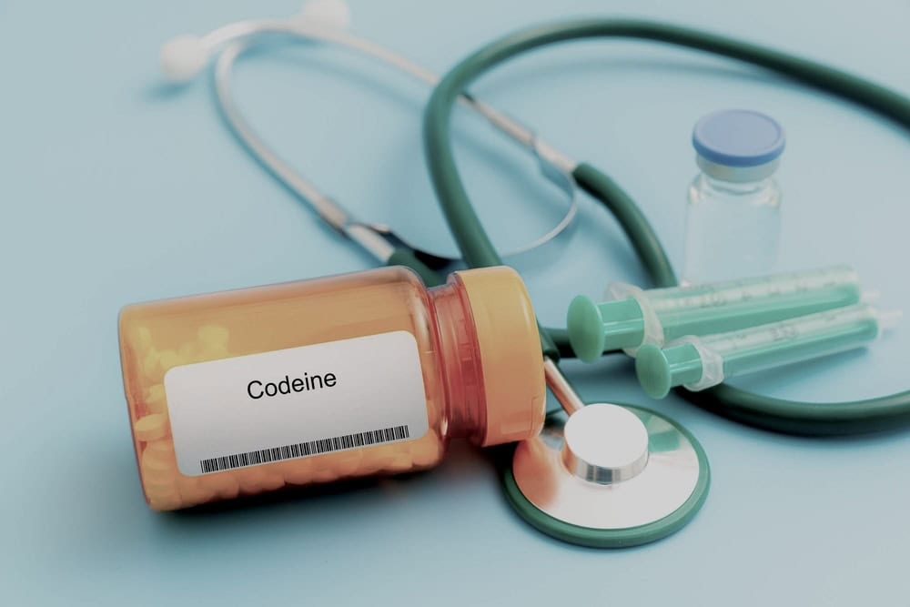 Codeine medicine container with white pills surrounded by medical equipment