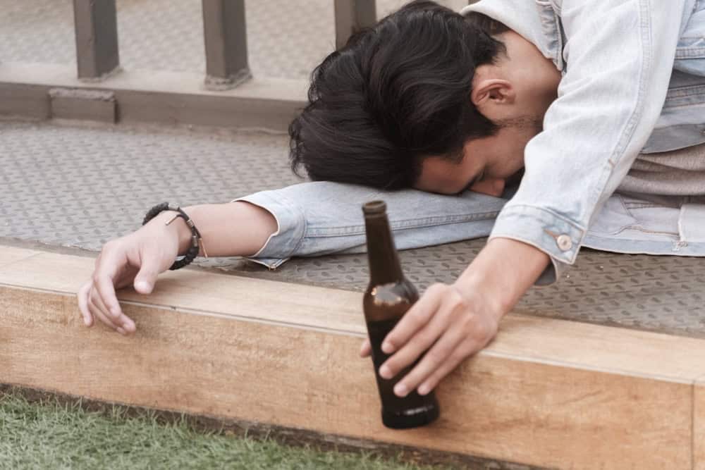 Drunk man on the floor holding a beer bottle