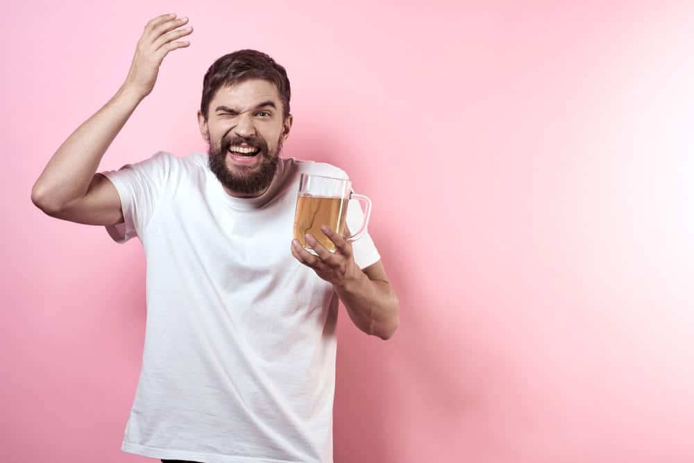 Man with white shirt holding a beer wondering if beer has 100% alcohol
