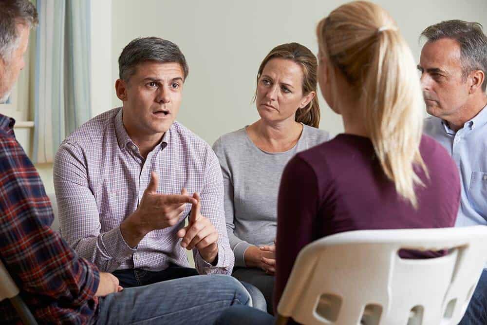 lighthousetreatment-7-signs-of-denial-in-an-addict-article-photo-members-of-support-group-sitting-in-chairs-having-meeting-366048554